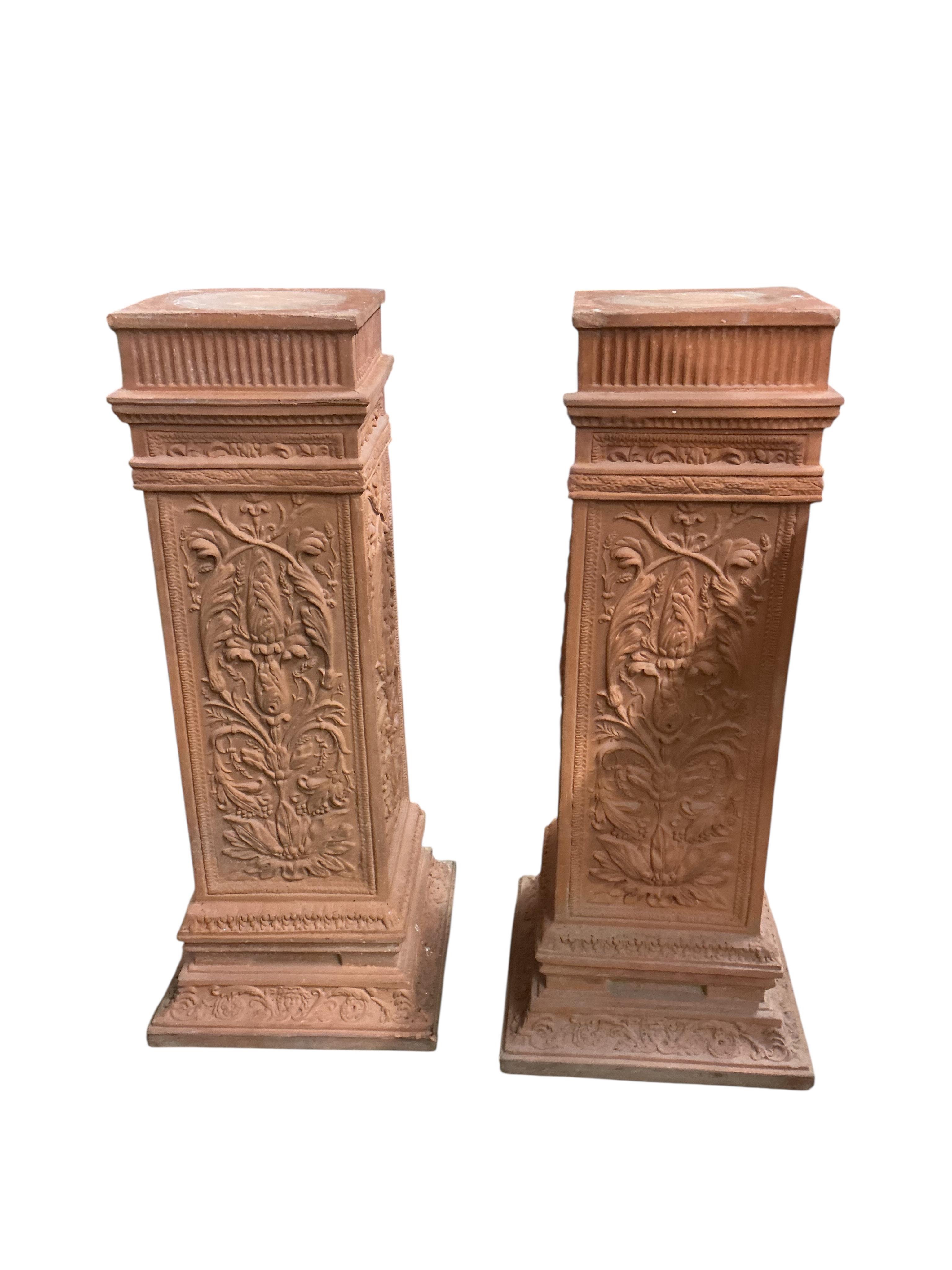 A pair of terracotta pedestals, decorated with panels of scrolling foliage, width 45cm, height 109cm